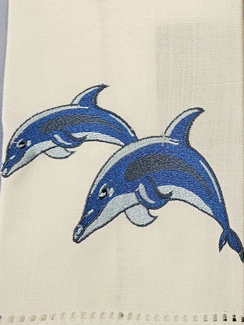 Hemstitched guest towel embroidered with two leaping dolphins