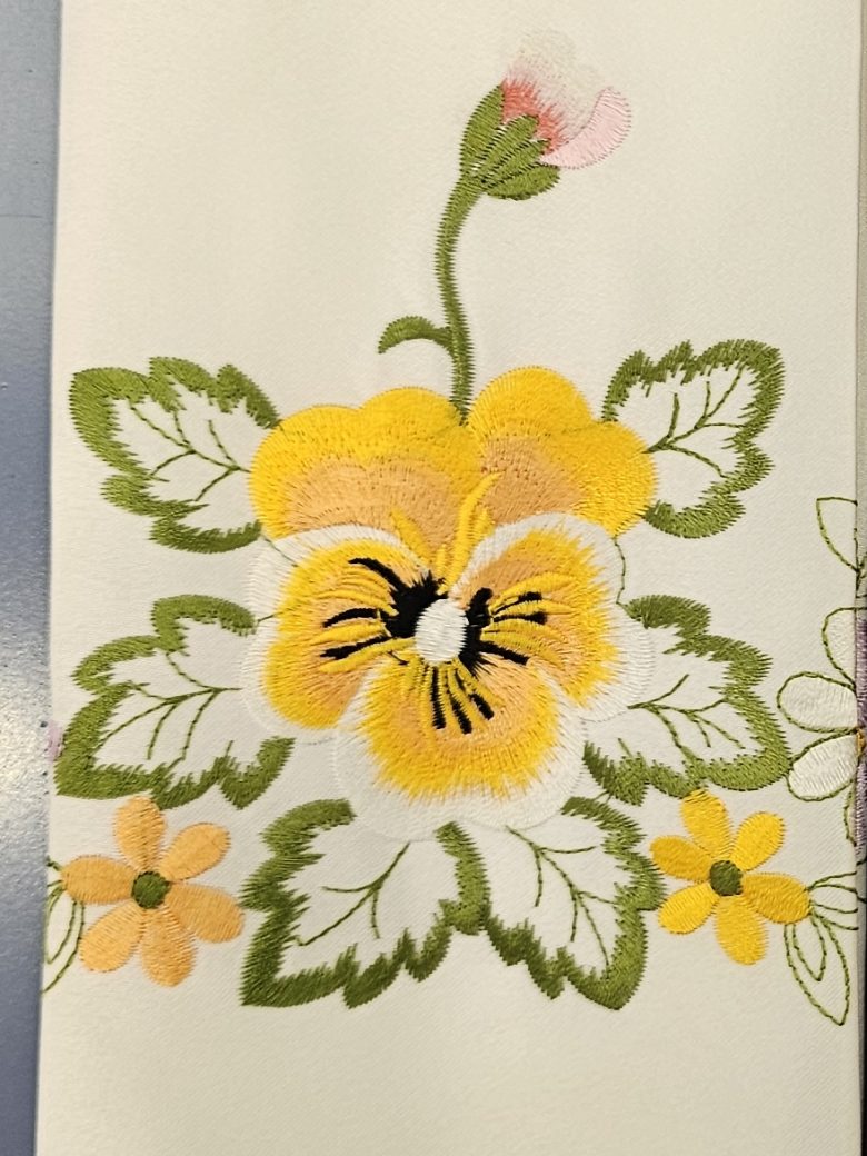 Ivory guest towel embroidered with a yellow pansy