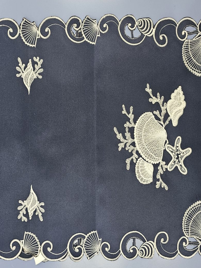Navy table runner embroidered with white shells, coral and starfish inside a cutwork shell border